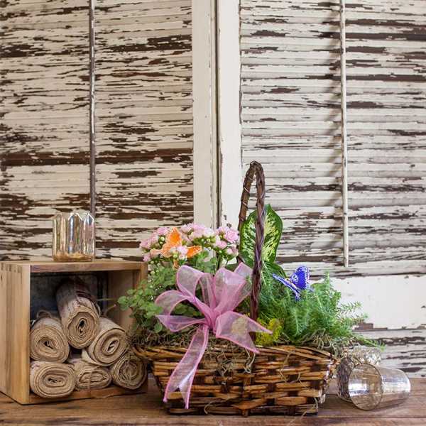 Basket of pink flowers with a pink ribbon and butterfly picks