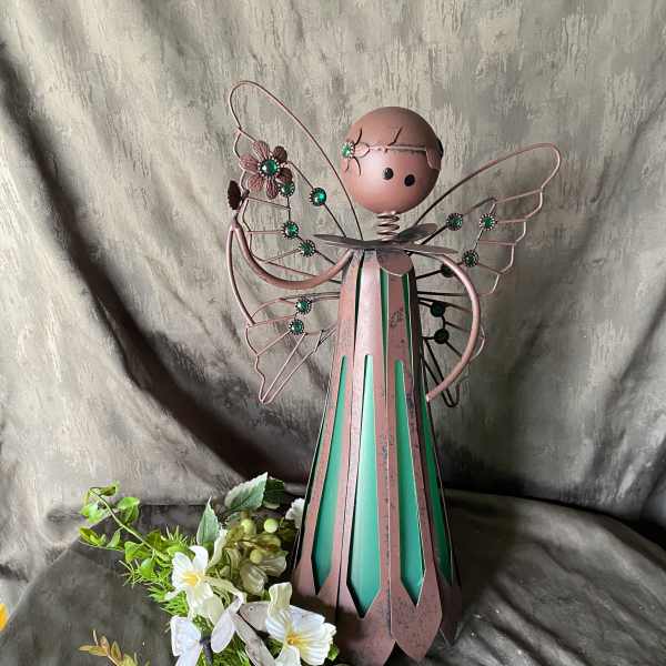 Metal angel figurine with white flowers and greenery at the base