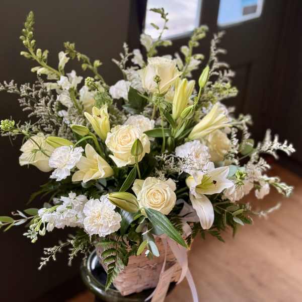 Cream roses and white lilies in a woven basket arrangement