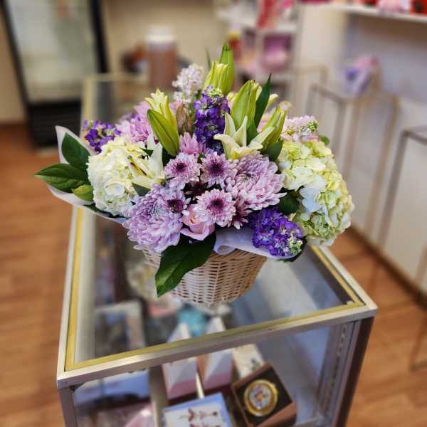 Basket arrangement of lilies, chrysanthemums, and hydrangeas in purple and white