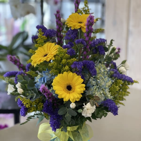 Bright mixed bouquet with yellow gerbera daisies in a blue vase