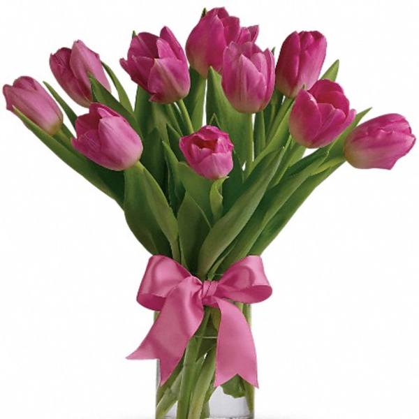 Pink tulips in a clear glass vase tied with a pink ribbon