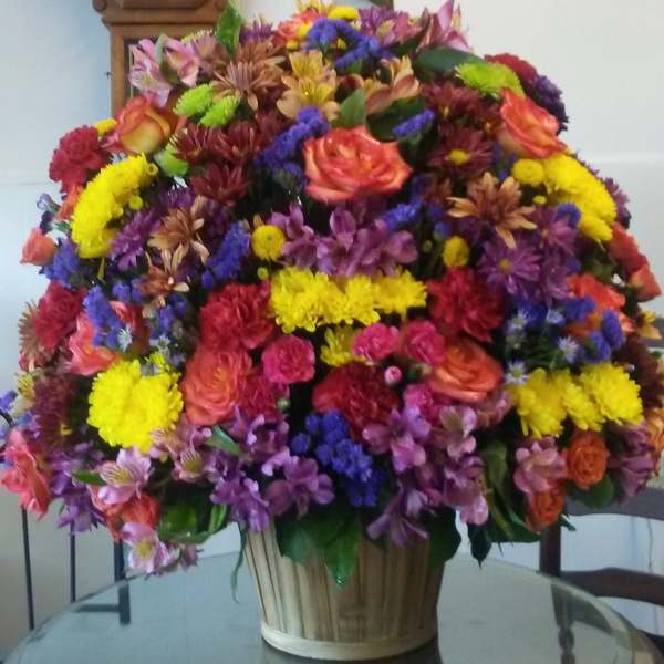Large mixed bouquet in a basket with pink, yellow, purple, and orange flowers
