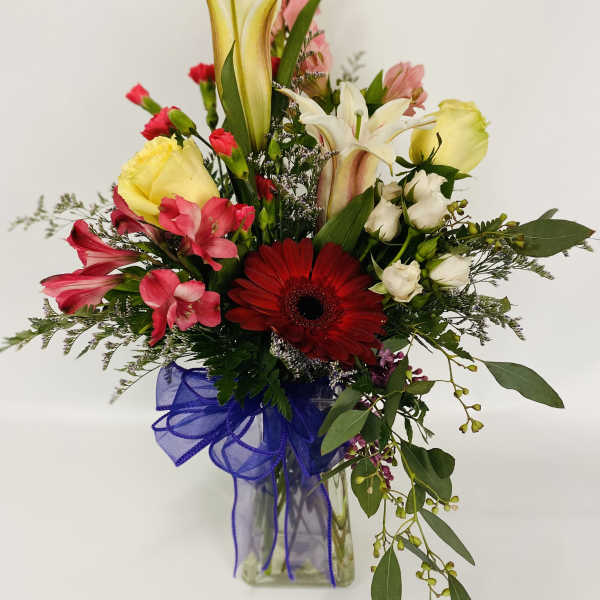 Mixed bouquet with lilies, gerbera daisy, and pink flowers in a glass vase