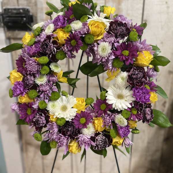 Circular floral wreath with purple, yellow, and white blooms