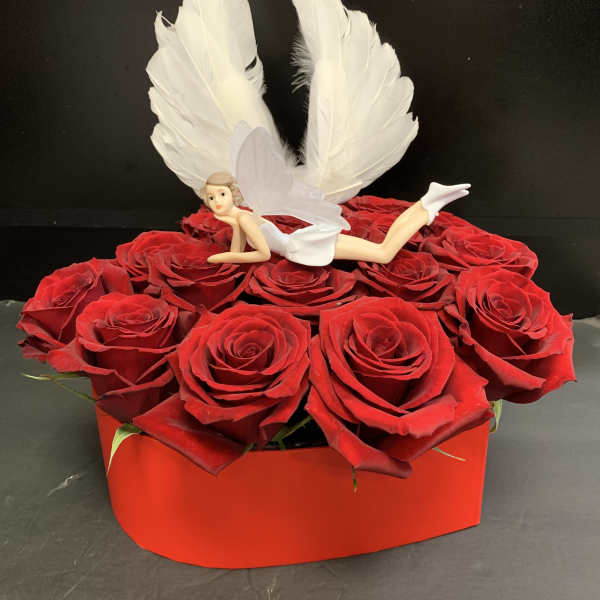 Red roses in a red box with a small fairy figurine and white wings