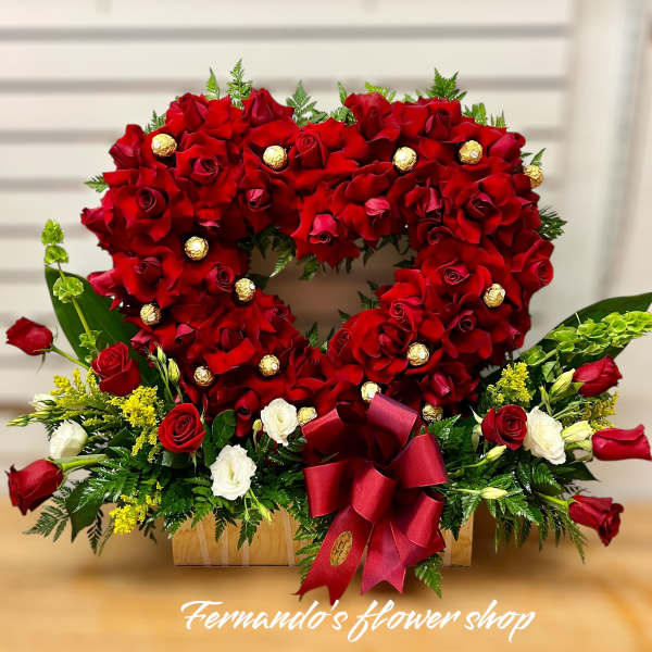 Heart-shaped arrangement of red roses with chocolates and base of red and white roses in a wooden box