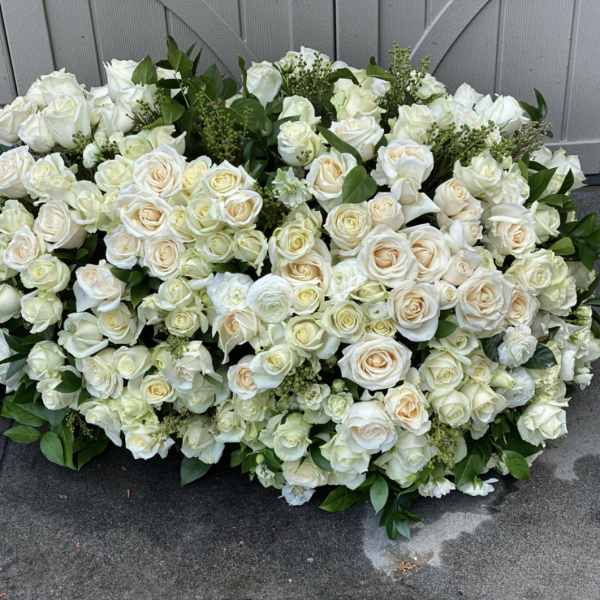 Large white rose arrangement with greenery on the ground