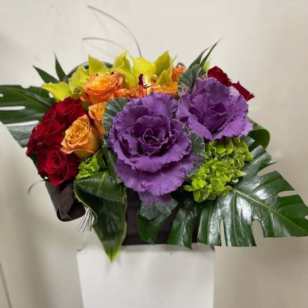 Bouquet of red and orange roses with purple ornamental cabbage in a box