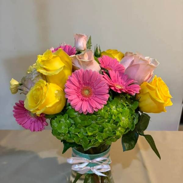 Bouquet of pink gerbera daisies and yellow roses in a glass vase