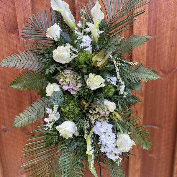 White floral standing spray with palm fronds and greenery