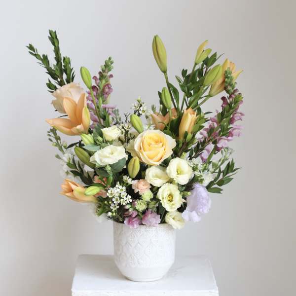 Mixed bouquet of lilies, roses, and lisianthus in a white vase