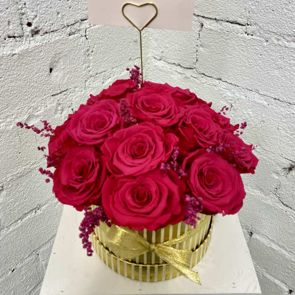 Hot pink roses in a gold striped box with a heart pick