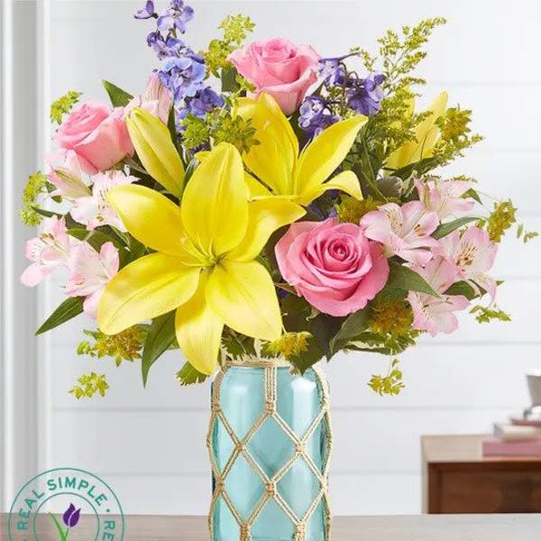 Bouquet of pink roses and yellow lilies in a blue glass vase