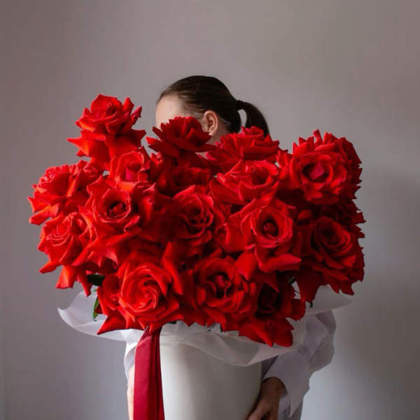 Large bouquet of red roses in a white hat box with a red ribbon