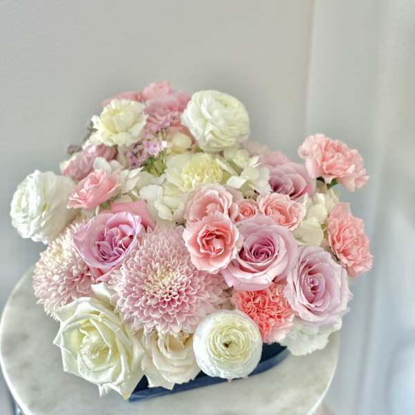 Pink and white bouquet of roses, carnations, and mums in a low box