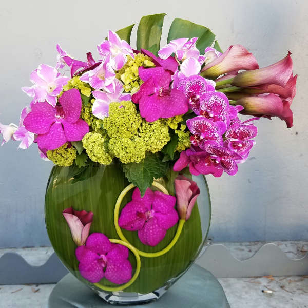 Pink orchids and calla lilies arranged in a glass vase