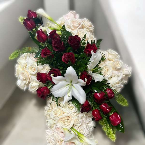 Cross-shaped arrangement of white roses with red roses and white lilies in the center
