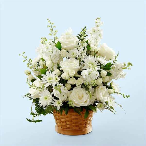 All-white roses, mums, and stock arranged in a woven basket