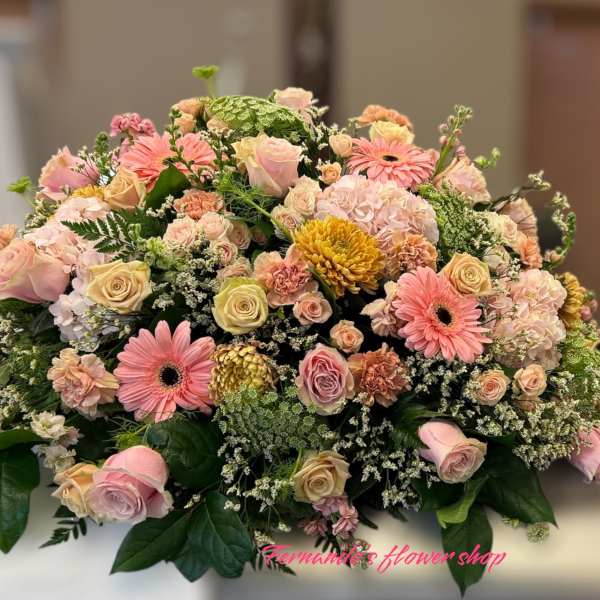 Low casket-style spray of pink and peach roses, gerberas, carnations, and mums with white filler flowers