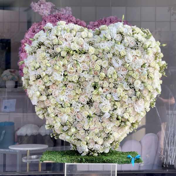 Heart-shaped arrangement of white and blush roses on a stand