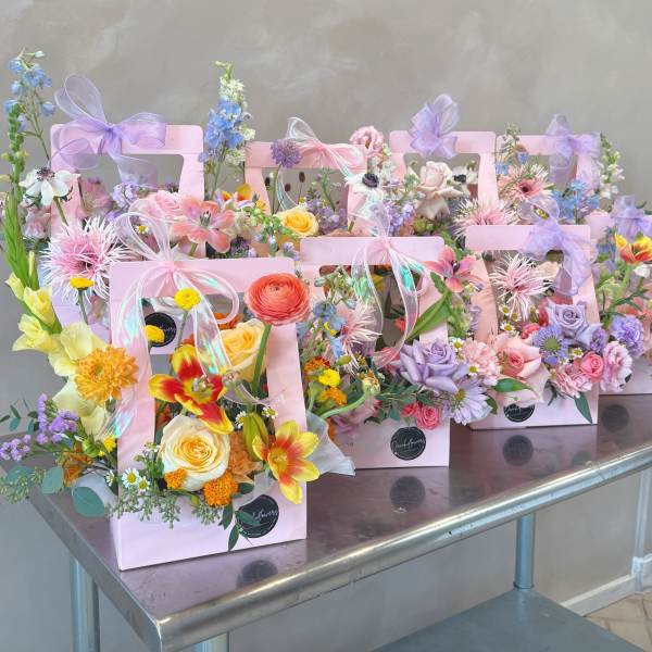 Pastel flower arrangements in pink gift boxes with ribbon bows