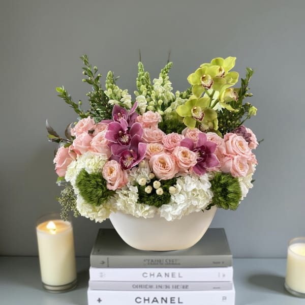 Pink roses and orchids in a white bowl vase with white hydrangeas
