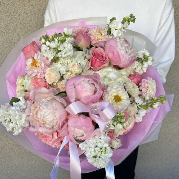 Large pink and white bouquet wrapped in lavender paper with a ribbon