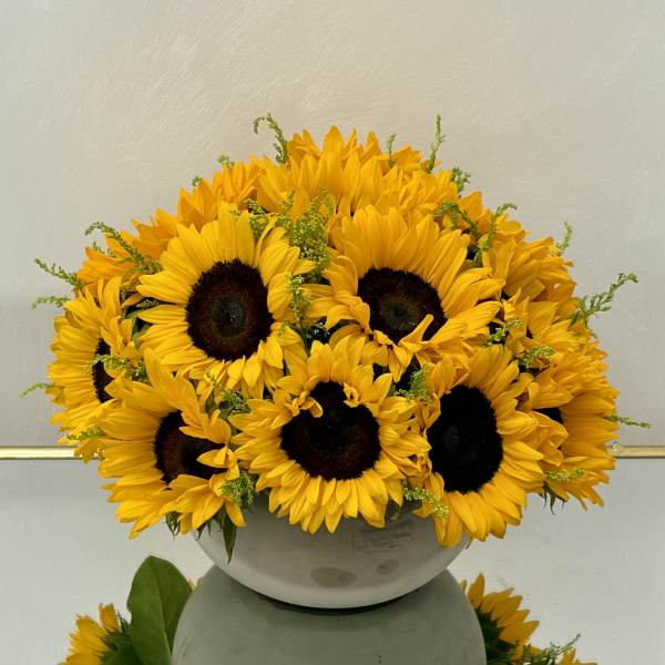 Bouquet of yellow sunflowers in a white bowl vase