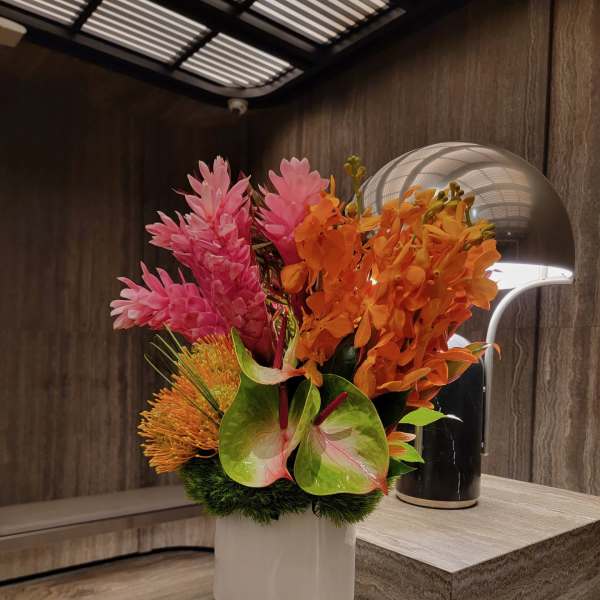 Tropical bouquet with pink and orange flowers in a white vase