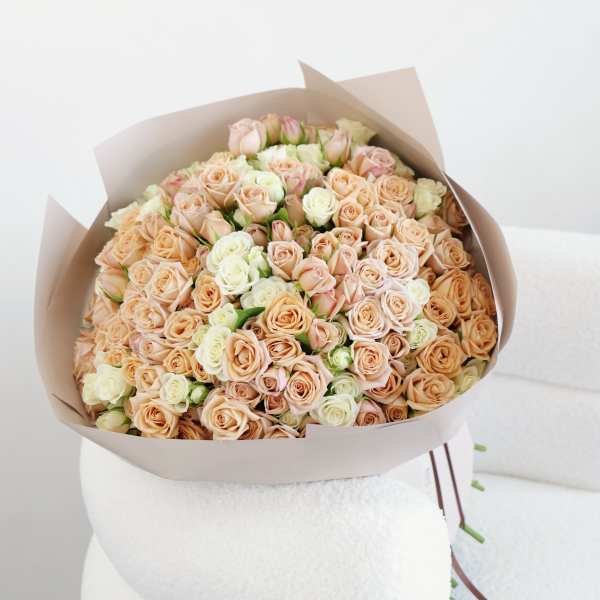 Bouquet of peach and white roses wrapped in beige paper