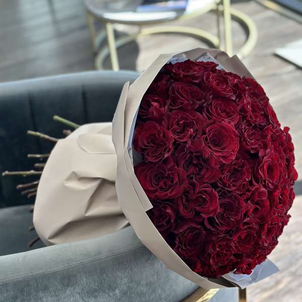 Large bouquet of deep red roses wrapped in white paper