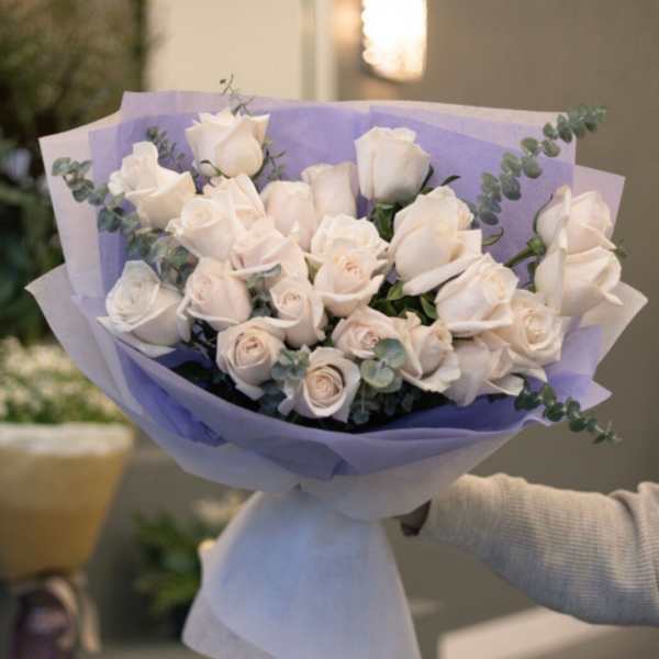 Bouquet of white roses wrapped in lavender paper