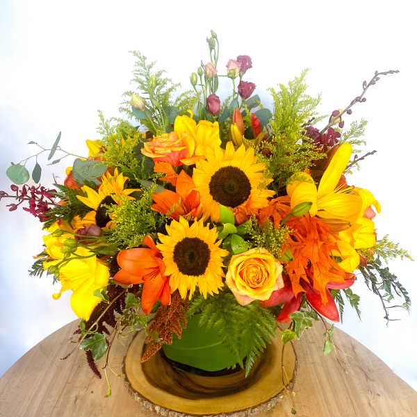 Bright mixed bouquet with sunflowers, roses, and lilies in a green vase