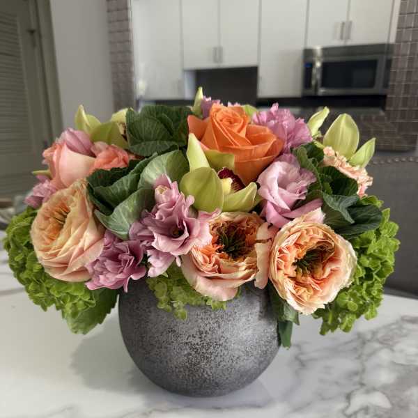 Mixed pink and peach flowers arranged in a gray vase