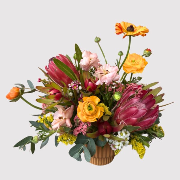 Colorful mixed bouquet in a ribbed vase with pink and orange blooms