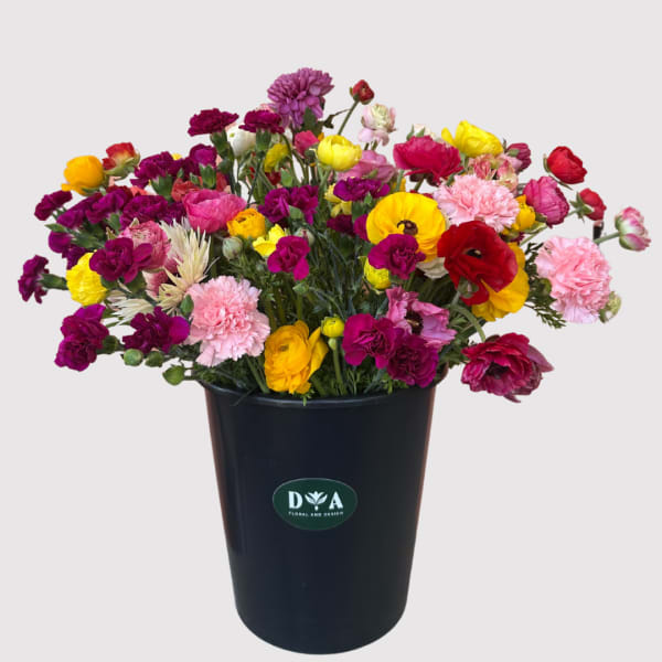 Bright mixed bouquet in a black container with pink, yellow, red, and purple blooms