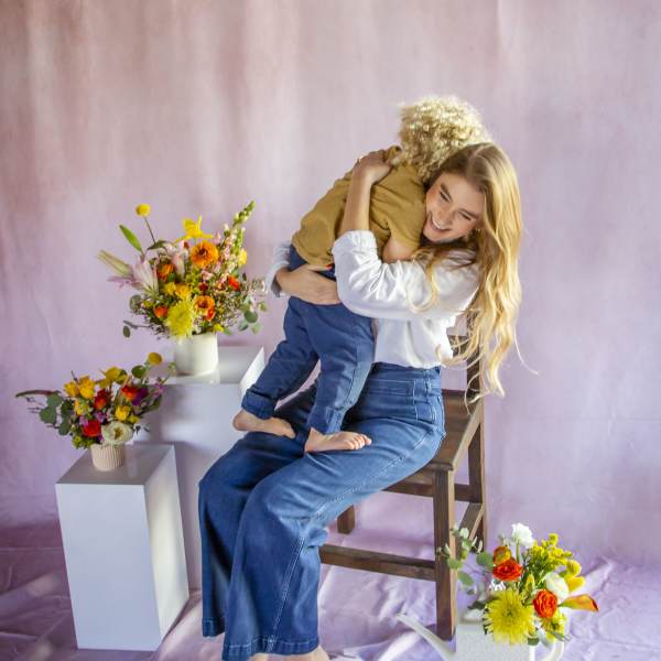 Woman holding a child beside colorful flower arrangements