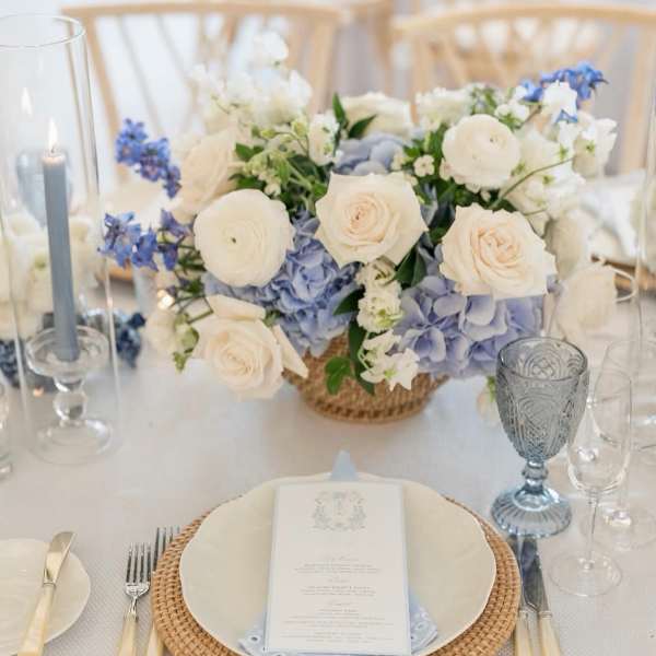 White and pale blue floral centerpiece on a table set for a formal event