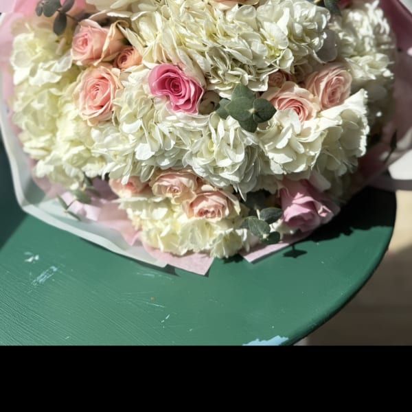 Bouquet of pale hydrangeas and pink roses wrapped in pink paper