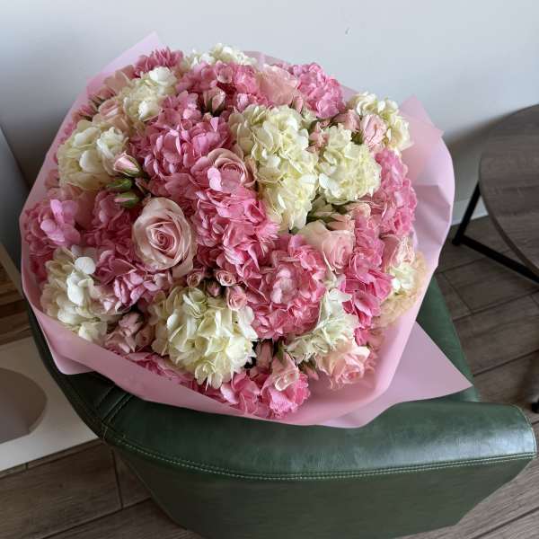 Large pink and white bouquet with roses and hydrangeas wrapped in pink paper