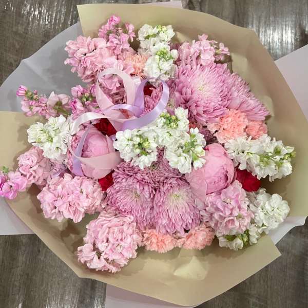 Pink and white mixed bouquet wrapped in beige paper with ribbon