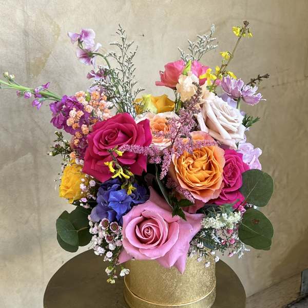 Colorful mixed bouquet of roses and small accent flowers in a gold box