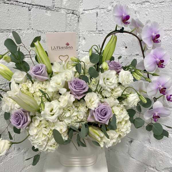 Lavender roses and white orchids in a white vase