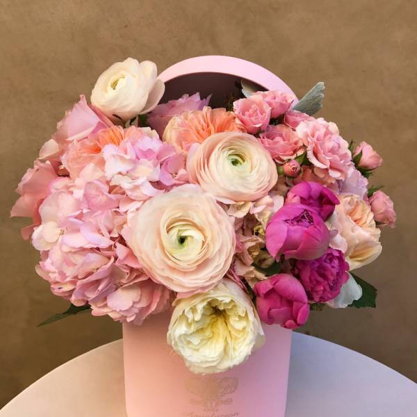 Pink and cream flower arrangement in a round hatbox