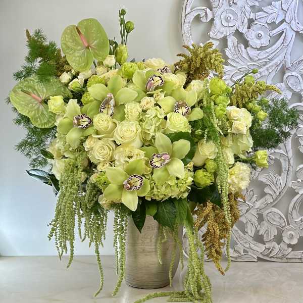 Large green and cream floral arrangement in a tall vase