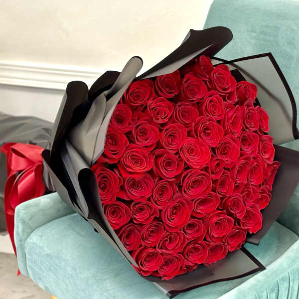 Large bouquet of red roses wrapped in black paper with a red ribbon