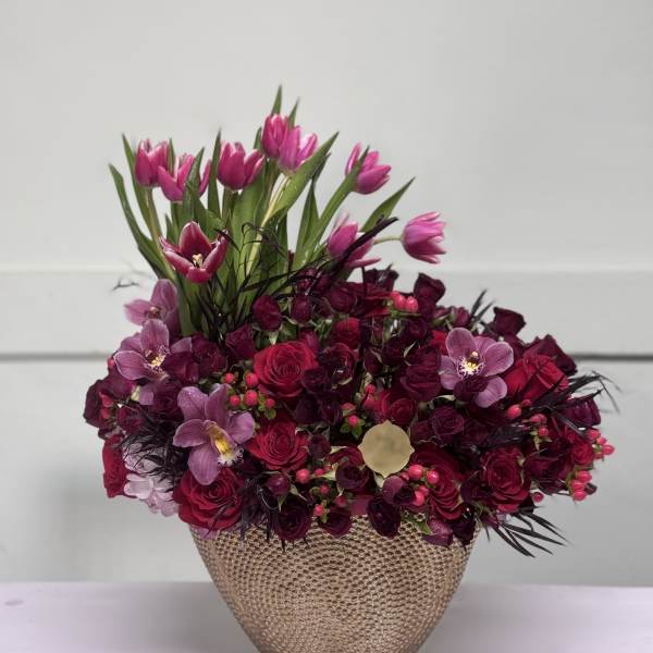 Pink tulips and roses arranged in a textured gold vase