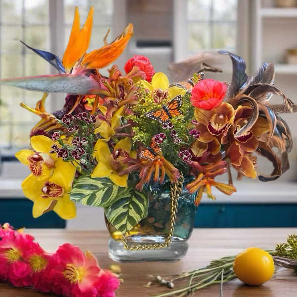 Tropical flower arrangement in a glass vase with orchids and bird-of-paradise blooms