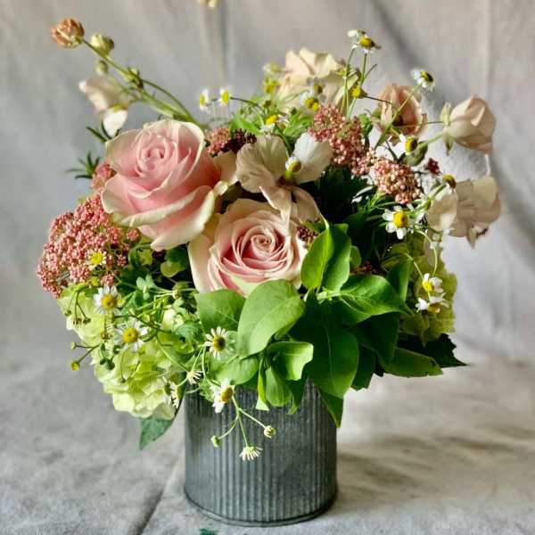 Pink roses and small white daisies arranged in a metal vase.